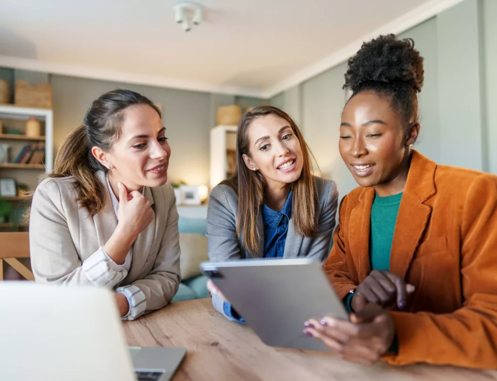 3 women reviewing their digital marketing strategy on a tablet