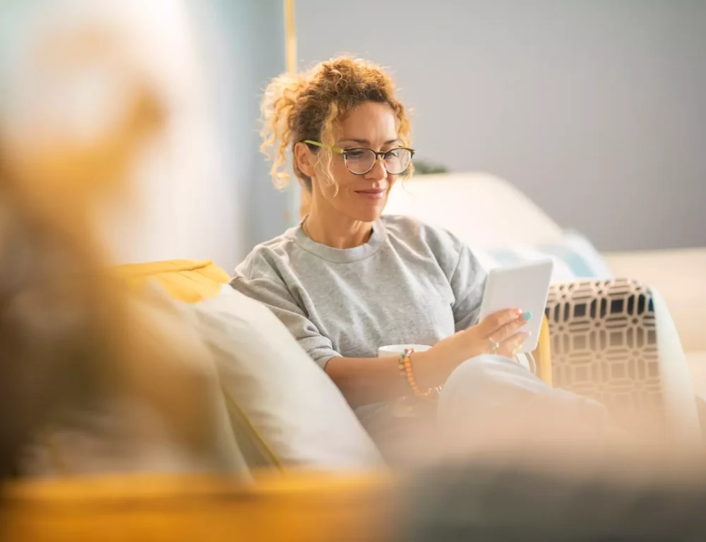 Woman sat on a sofa looking at a tablet