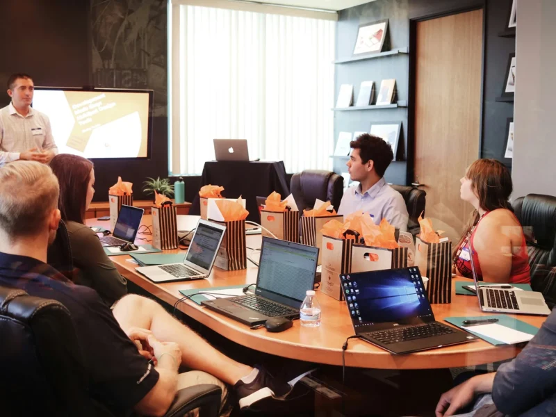 Presentation in an office with attendees sitting around a table.