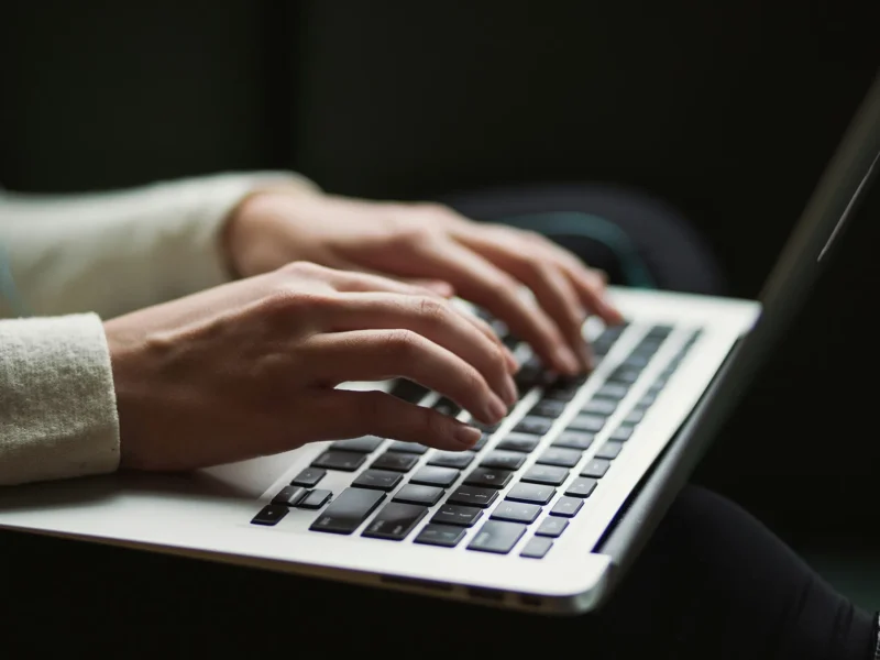 Hands typing on a laptop keyboard.